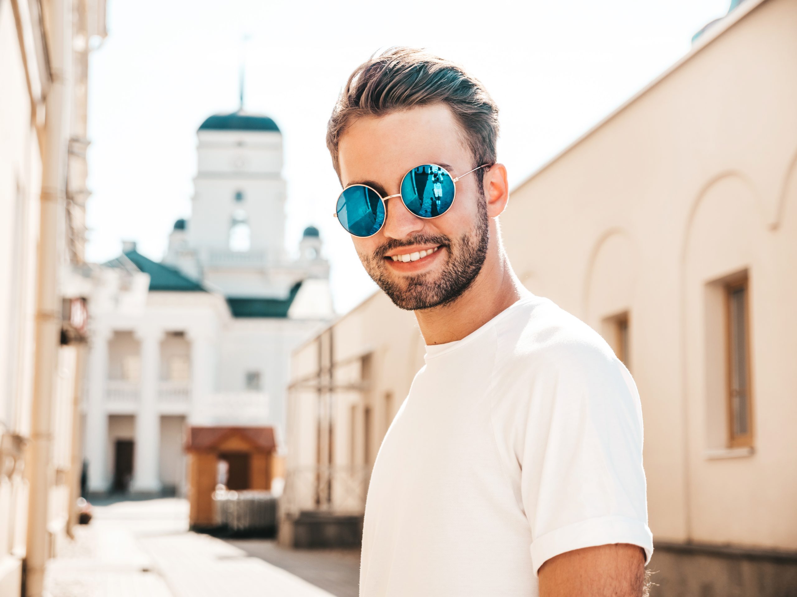 Confident man with perfect hairstyle, wearing sunglasses and smiling on a sunny day