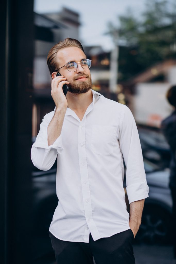 man in white shirt with attractive hairstyle talking on the phone