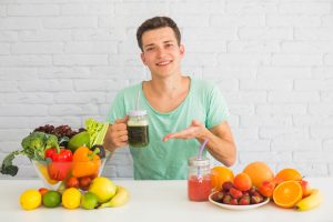 Man with healthy foods on table including green smoothie showing nutrition for hair growth