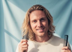 Man examining hair texture and scalp health in mirror for evidence-based hair care routine